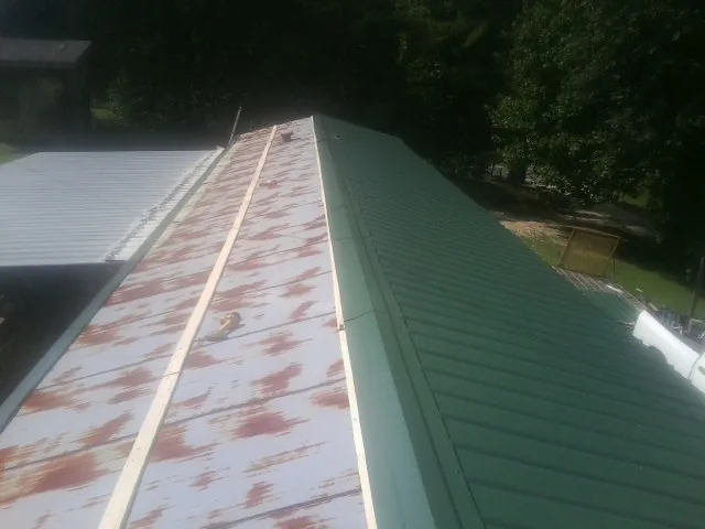 Old rusted panels beside newly installed green metal roofing — Wind Damage Roof Repair by Roofing Brothers in Kearney