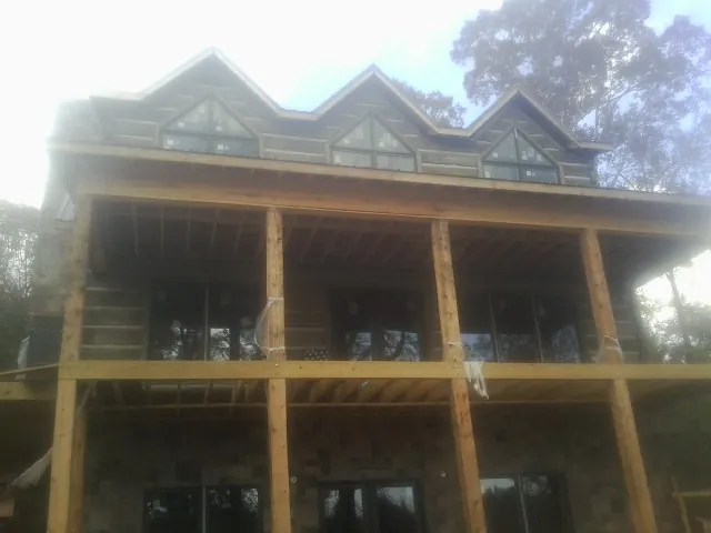 Dormers and porch framing on a large log home under construction — Roof Coating work by our crew in Kearney