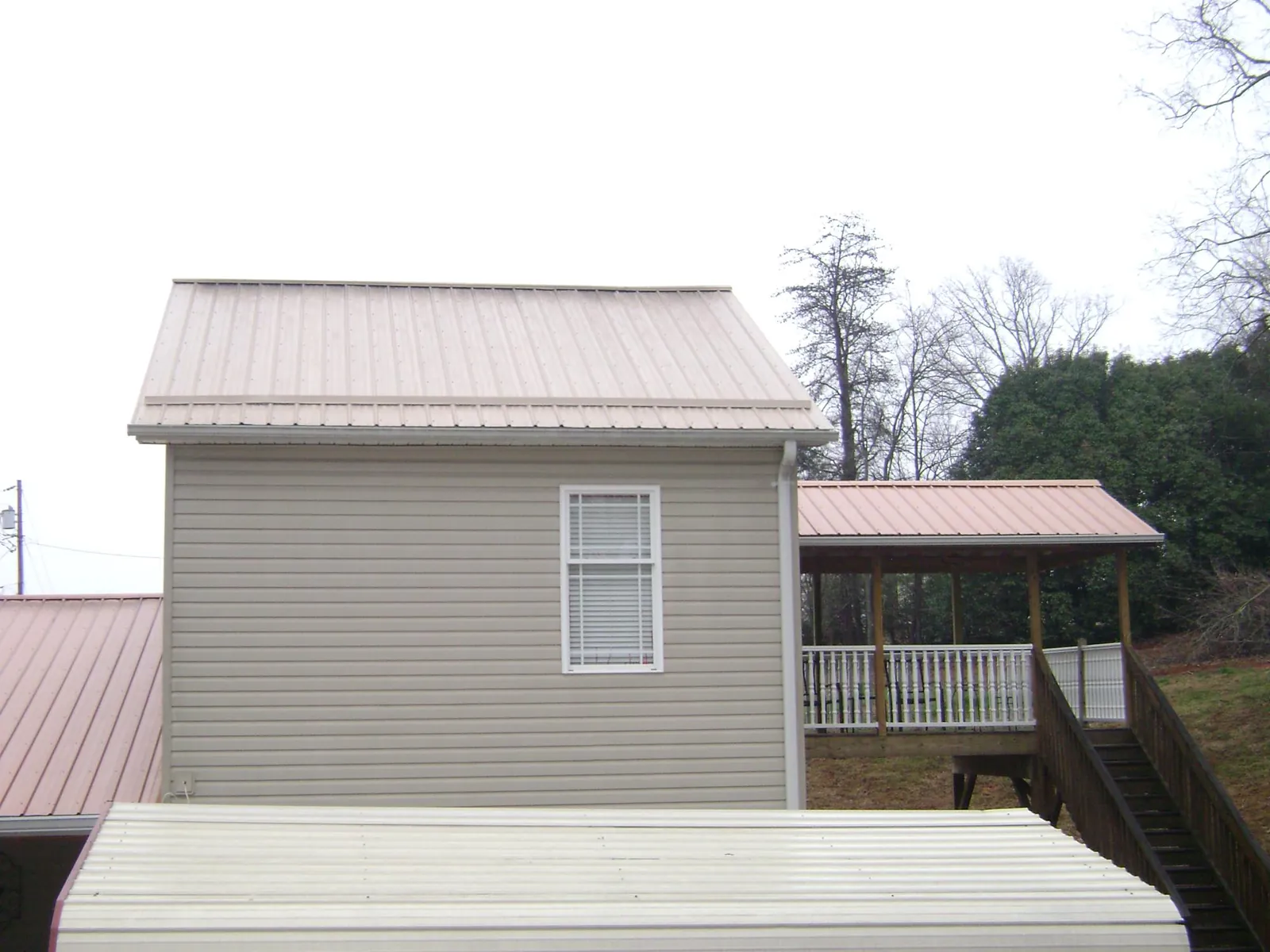 Tan metal roofs on a two story addition and attached porch, from a Roof Replacement job in Kearney
